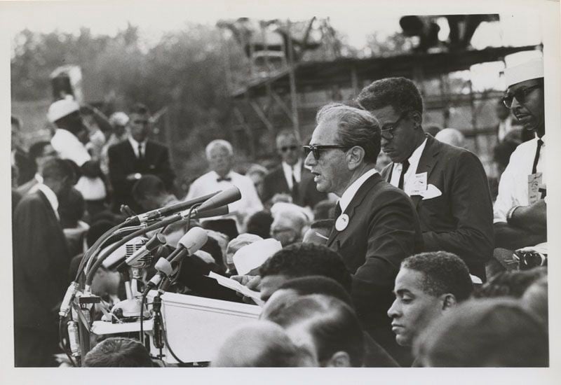 Rustin stands behind speaker Joachim Prinz during the March on Washington.