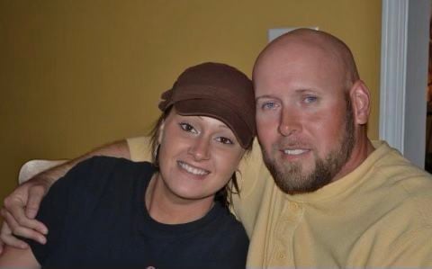 Brunette girl wearing a hat posing next to bald man with blue eyes