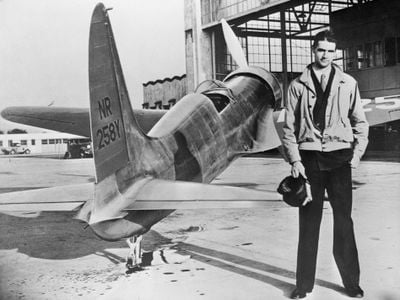 Howard Hughes stands with his first plane, the H-1.