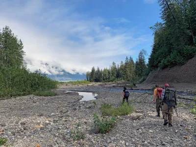 Researchers hike near a creek that formed after a glacier retreated.
