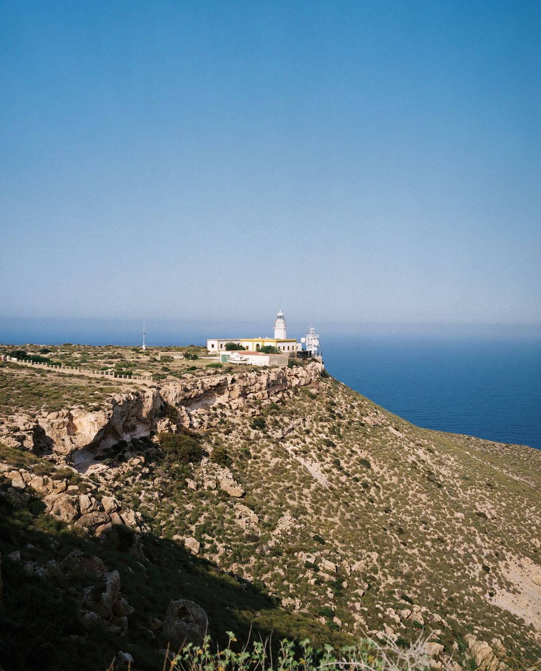 a lighthouse sits on rugged terrain