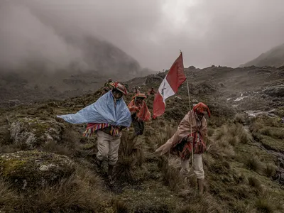 Members of the Quelcanca community in Peru return from planting trees in the mountains, hoisting their country&#39;s flag.